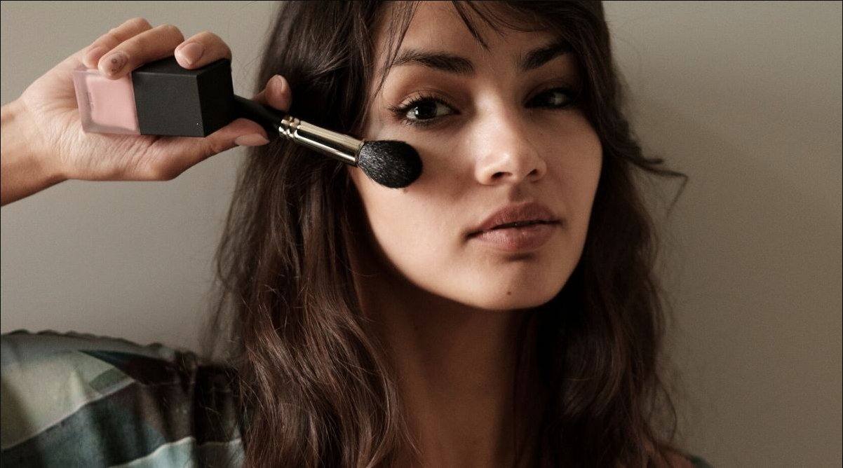 Woman brushing face with makeup brush
