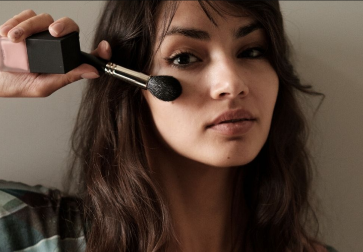 Woman brushing face with makeup brush